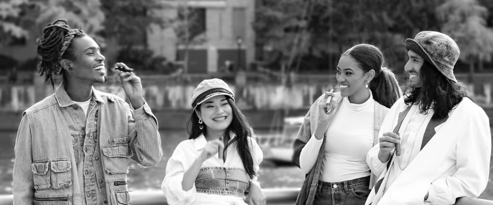 水辺で語らう4人の男女のモノクロ写真